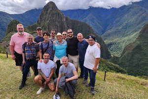 A group of people posing for a photo in front of machu picchu.