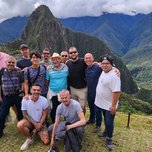 A group of men posing for a photo in front of the mountainous landscape of machu picchu.
