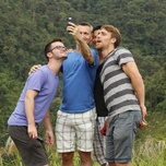 Three men taking a selfie with a forested hillside in the background.