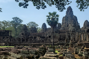 Ancient temple ruins amidst a forest under a clear sky.