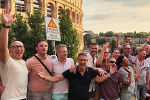 A group of people standing in front of the coliseum.