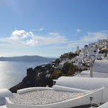 Whitewashed buildings with blue domes overlooking a calm sea on a sunny day in santorini, greece.