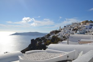 Whitewashed buildings with blue domes overlooking a calm sea on a sunny day in santorini, greece.