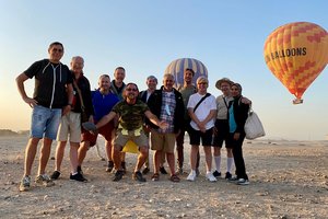 A group of people standing in front of a hot air balloon.