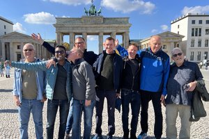 A group of men posing for a photo in front of the brandenburg gate.