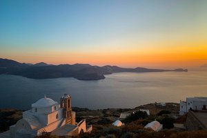 Sunset view over a coastal landscape with a traditional whitewashed church in the foreground.