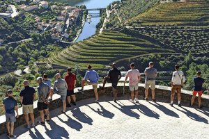 A group of people standing on top of a hill overlooking a river.