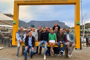 Group of people posing for a photo at a framed viewpoint with table mountain in the background, cape town, south africa.