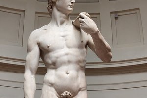 A statue of a naked man in a museum.