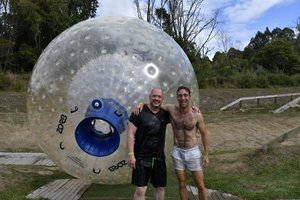 Two men standing in front of an inflatable ball.