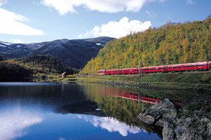 A train on the tracks by a lake.