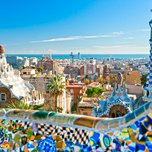 A panoramic view of barcelona seen from park güell with colorful ceramic mosaics in the foreground.