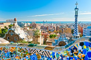 A panoramic view of barcelona seen from park güell with colorful ceramic mosaics in the foreground.