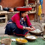 A woman in traditional attire kneels while working with natural dyes and textiles.