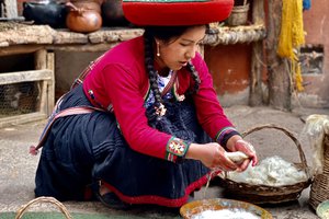 A woman in traditional attire kneels while working with natural dyes and textiles.