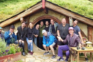 A group of people posing in front of a hobbit house.