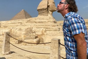 A man kissing a statue of a sphinx.