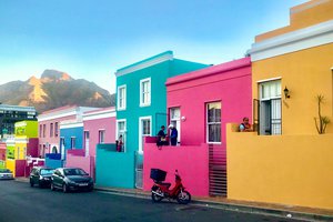 Colorful houses line a street with a mountain backdrop at sunset.