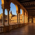Sunlight bathes the arched gallery of the plaza de españa in Seville, highlighting the ornate architecture.