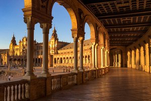 Sunlight bathes the arched gallery of the plaza de españa in Seville, highlighting the ornate architecture.