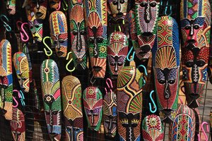 A bunch of colorful masks hanging on a wall.
