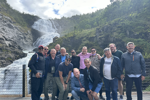 Group of men stand in front of waterfall