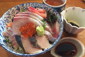 A bowl of assorted sashimi served with soy sauce and wasabi.
