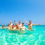 Group of people enjoying a swim in clear turquoise waters.