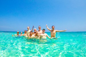 Group of people enjoying a swim in clear turquoise waters.